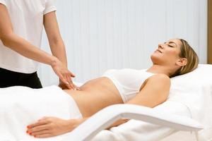 donna di mezza età con un massaggio del ventre in un salone di bellezza.