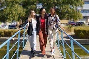 sorridenti amici diversi che si abbracciano mentre si passeggia su una stretta passerella foto