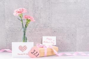 scatola regalo fatta a mano per la festa della mamma auguri a sorpresa fotografia - bellissimi garofani in fiore con scatola di nastro rosa isolata su carta da parati grigia design, primo piano, spazio di copia foto