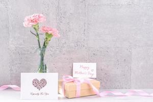 scatola regalo fatta a mano per la festa della mamma auguri a sorpresa fotografia - bellissimi garofani in fiore con scatola di nastro rosa isolata su carta da parati grigia design, primo piano, spazio copia, mock up foto