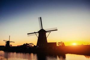 mulino olandese al tramonto dal canale di Rotterdam. Olanda foto