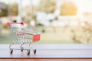 concetto di acquisto - carrello o carrello vuoto sul tavolo di legno marrone. i consumatori dello shopping online possono acquistare da casa e dal servizio di consegna. con spazio di copia foto