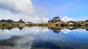 rifugio alpino si specchia in un piccolo lago di montagna foto