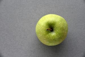 una mela verde su sfondo grigio