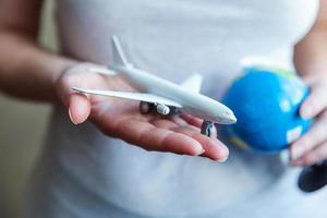 mani di donna femminile che tengono piccolo aereo modello giocattolo e mappa del globo. viaggio in aereo vacanza weekend viaggio avventura viaggio biglietto tour aviazione concetto di consegna. simbolo di libertà internazionale. foto