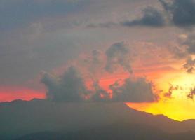 tramonto rosso con nuvole e skyline di montagne foto