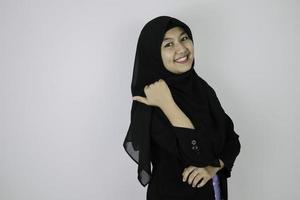 la giovane donna asiatica sorridente dell'islam che indossa il velo è sorriso e indica dietro. foto