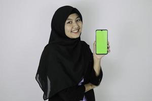 donne d'affari islamiche asiatiche felici che puntano e mostrano lo schermo vuoto sul telefono. foto