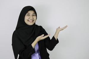 la giovane donna asiatica felice dell'islam che indossa il velo è sorriso e indica accanto. foto