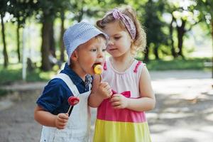 i bambini felici assaggiano le caramelle su un bastone foto