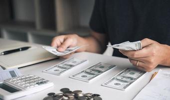 gli uomini asiatici tengono le banconote in contanti e le mettono sul tavolo con l'idea di risparmiare denaro. foto