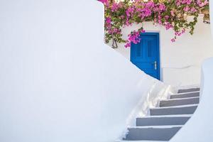 vecchia porta blu e fiori rosa, architettura greca tradizionale, isola di santorini, grecia. strada romantica panoramica di oia, santorini, case bianche porta blu. vacanze di viaggio di sfondo artistico di belle arti foto