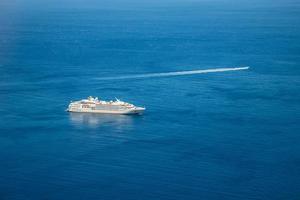 veduta aerea della bellissima nave da crociera bianca, crociera di lusso nella luce del sole mattutino del mare blu profondo dell'oceano, viaggi turistici in vacanza in estate. foto