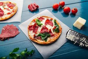 vista dall'alto della pizza su uno sfondo vintage in legno blu alla moda con ingredienti per pizza. foto