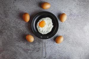 uova fritte in padella e uova fresche sul tavolo foto