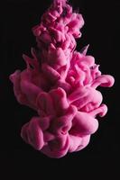 goccia di inchiostro rosa in acqua limpida e sfondo nero. immagine astratta per riferimento di sfondo o colore. foto