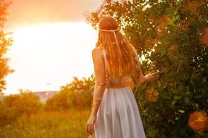 una donna con i capelli lunghi sta con le spalle al tramonto foto