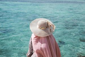 turista donna in cappello estivo godendo di una vista chiara dell'acqua di mare all'isola di karimun jawa foto