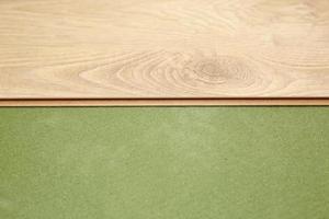 installazione di pavimenti in legno laminato o parquet nella stanza su base verde. assemblare i pannelli in modo rapido e semplice - pavimentazione economica. posa di pavimenti in laminato in casa foto
