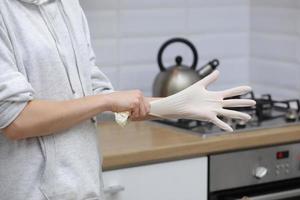 primo piano della giovane donna che indossa il grembiule per la pulizia del piano di lavoro della cucina. disinfezione mobili di casa. messa a fuoco selettiva. foto