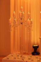 sul tavolo c'è un candeliere in cristallo con candele bianche. decorazione per vacanze o feste con luce. messa a fuoco selettiva. foto