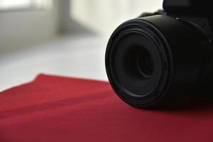 fotocamera reflex nera con obiettivo su sfondo rosso foto