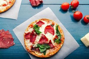 vista piatta della pizza su uno sfondo vintage in legno blu alla moda con ingredienti per pizza. foto