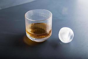 cubetto di ghiaccio a forma di sfera e vista ravvicinata del whisky dallo studio. foto