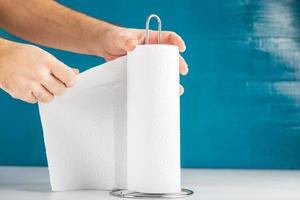 una mano anonima sta strappando un tovagliolo di carta, lo spazio per la copia del concetto di igiene include. foto