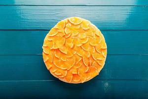 Vista dettagliata del primo piano Cheesecake o budino all'arancia a fette, decorato con frutta arancione matura. foto