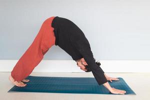 giovane uomo bianco dai capelli lunghi caucasico sta eseguendo yoga in uno studio o in una casa. foto