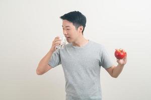 giovane uomo asiatico con bicchiere d'acqua e mela a portata di mano foto