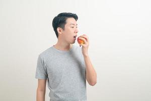 giovane uomo asiatico con bicchiere d'acqua e mela a portata di mano foto