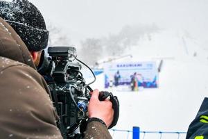 operatore di ripresa filma la gara di sci nella stazione sciistica in condizioni di freddo nevoso estremo foto