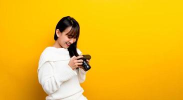 il fotografo asiatico della ragazza guarda le foto della fotocamera con un sorriso felice. concetto di fotografia