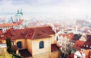 il tetto rosso di praga. vista panoramica dal castello, repubblica ceca. giornata estiva con nuvole di cielo blu e fitta nebbia in città. foto