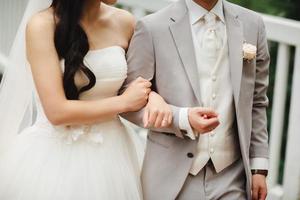 sposi. la sposa con il bouquet da sposa tiene il braccio dello sposo. coppia di sposini alla moda. concetto di matrimonio foto