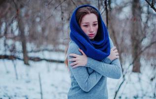 Ritratto di giovane ragazza dai capelli rossi con le lentiggini che indossa una sciarpa di lana lavorata a maglia blu nella giornata invernale. foto