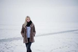 ritratto di giovane eleganza ragazza bionda in uno sfondo di pelliccia fiume nebbioso sul ghiaccio d'inverno. foto