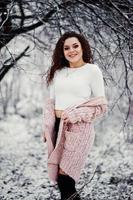sfondo ragazza bruna riccia neve che cade, indossare un maglione caldo lavorato a maglia, minigonna nera e calze di lana. modello in inverno. ritratto di moda con tempo nevoso. foto dai toni di instagram.