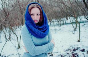 Ritratto di giovane ragazza dai capelli rossi con le lentiggini che indossa una sciarpa di lana lavorata a maglia blu nella giornata invernale. foto