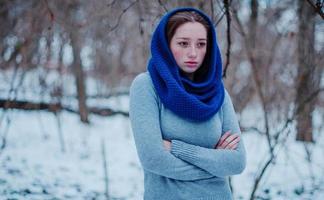 Ritratto di giovane ragazza dai capelli rossi con le lentiggini che indossa una sciarpa di lana lavorata a maglia blu nella giornata invernale. foto