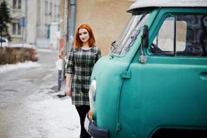 giovane ragazza dai capelli rossi poste su sfondo abito a scacchi vecchio minivan ciano retrò. foto