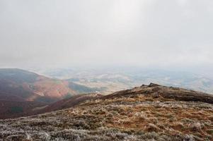 collina di montagna con erba gelata e luce solare dalle nuvole foto