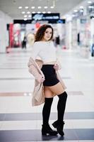 giovane modella riccia posata su minigonna in un grande centro commerciale. foto
