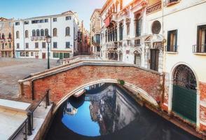 gondole tradizionali sul canale stretto tra case storiche colorate a venezia italia foto