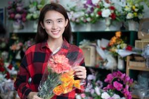 donna sorridente fiorista piccola impresa proprietario di un negozio di fiori e giovane fiorista che esamina i fiori al negozio foto