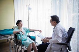 i medici chiedono e spiegano della malattia a una paziente distesa a letto in ospedale. foto