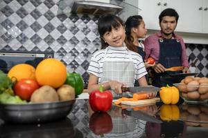 la famiglia felice ha papà, mamma e la loro piccola figlia che cucinano insieme in cucina foto