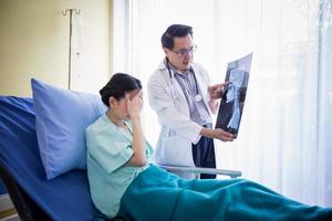 il dottore sta spiegando i risultati della radiografia cerebrale a una paziente sdraiata a letto in un ospedale
